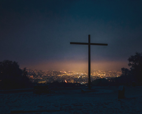 A christian symbol or cross above the glowing city lights during a stormy night in Stuttgart, Germany